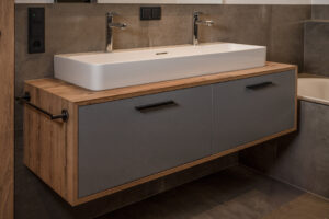 Bathroom cabinet with grey front, oak frame and chrome faucet