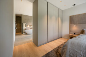 Bedroom ensuite bathroom divided by matt grey build-in closet