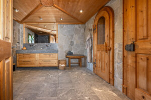 Chalet bathroom with solid stone flooring and washbasin. Oak furniture and traditional doors.
