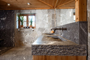 Luxury chalet bathroom with natural stone washbasin and rough edge design.