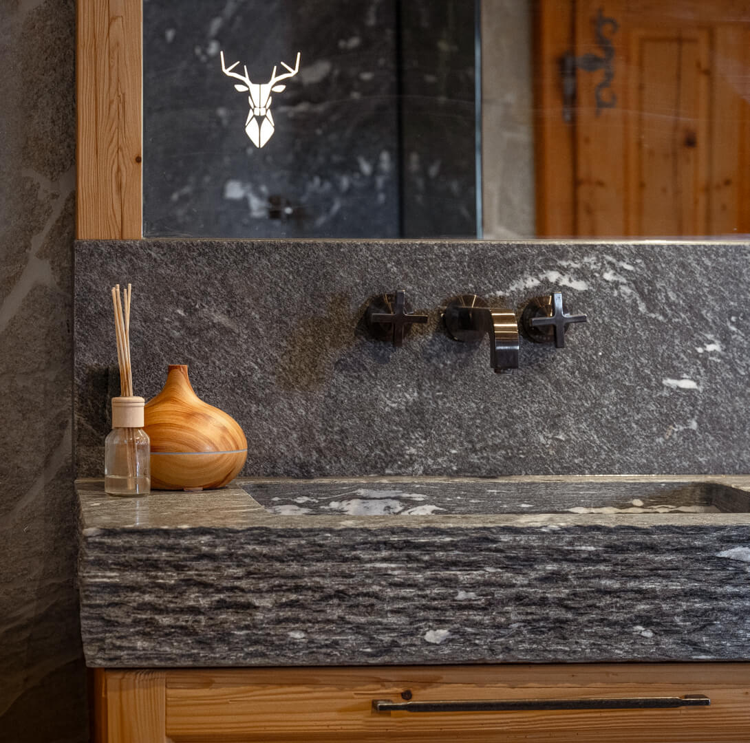 Rustic alpine bathroom with stone sink and oak furniture.