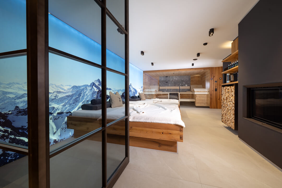 Chalet relaxation room with sauna, loft doors, and cozy fireplace.