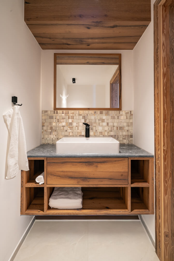 Chalet bathroom with oak furniture, natural stone, and mother-of-pearl tiles.