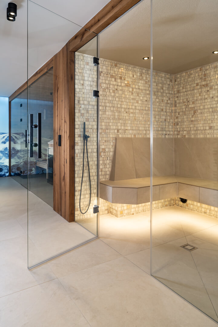 Steam bath with glass and oak façades and mother-of-pearl tiles and glassdoor.