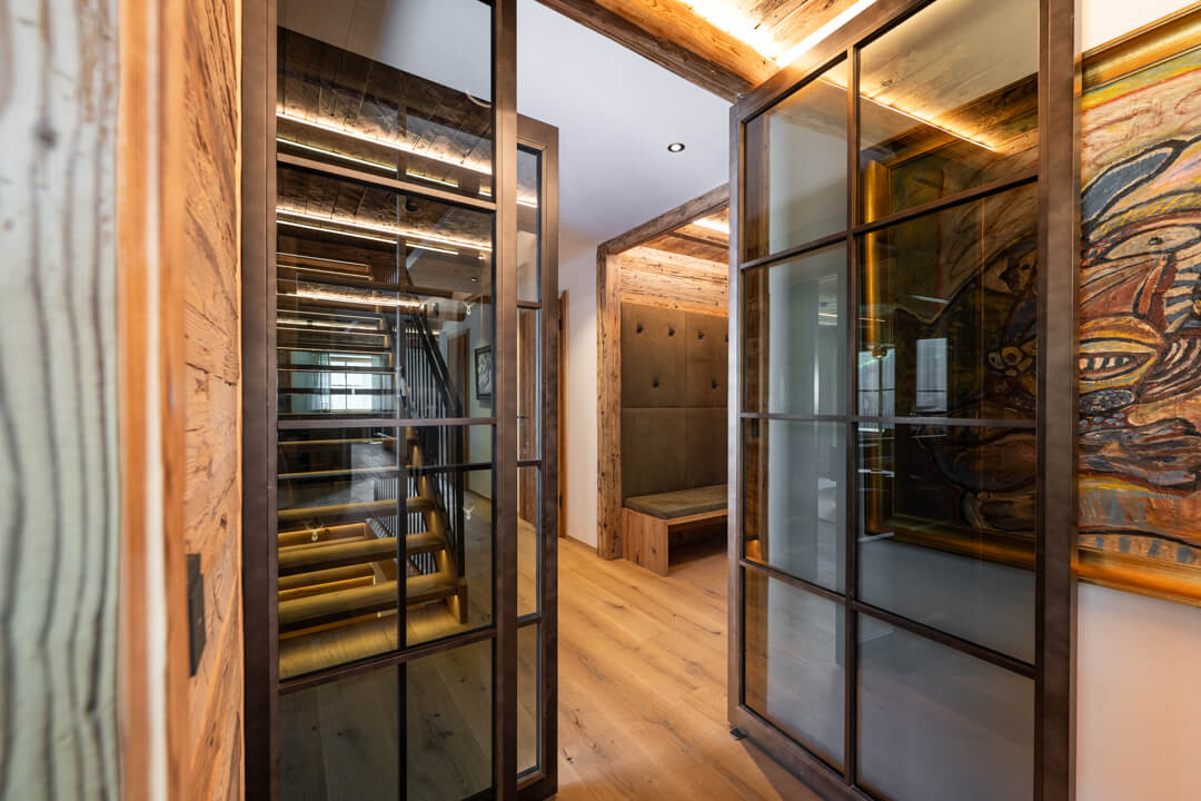 Chalet entrance with reclaimed wood and loft-style doors with smoked glass.