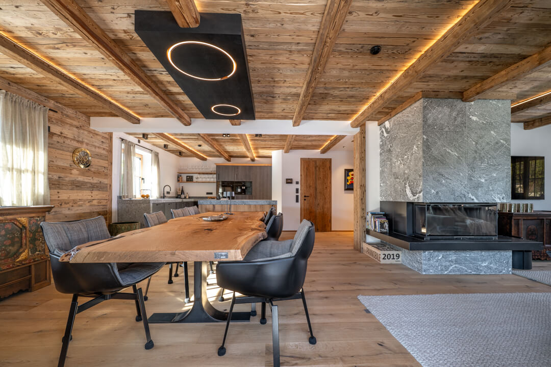 Chalet interior with kitchen island, natural stone countertop, integrated oak table, and massive stone fireplace.