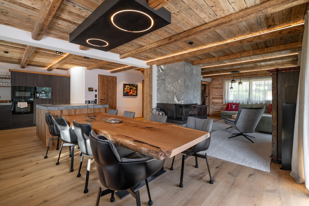 Chalet interior with kitchen island, natural stone countertop, and integrated oak table.