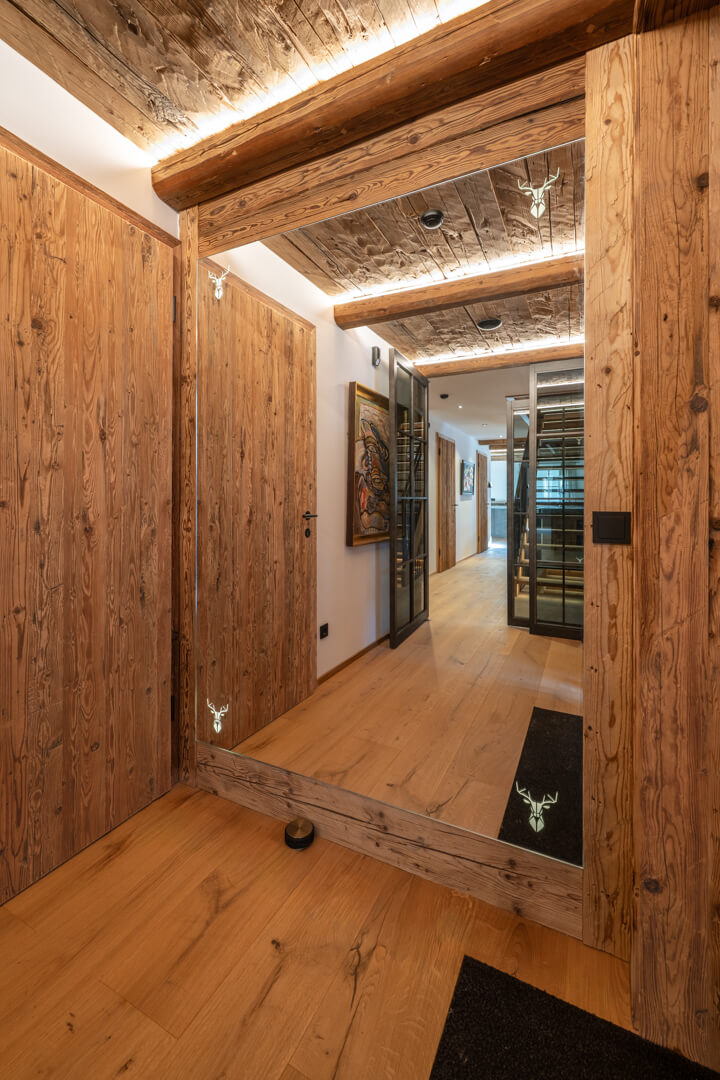 Chalet entrance with reclaimed wood, mirror, and illuminated deer motifs.