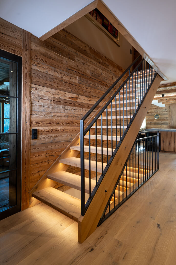 Oak staircase with steel railing, oak flooring, reclaimed wood paneling, and loft-style steel-look doors.