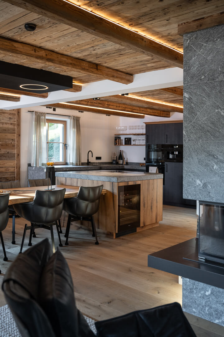 Chalet interior with kitchen island, natural stone countertop, and integrated oak table.