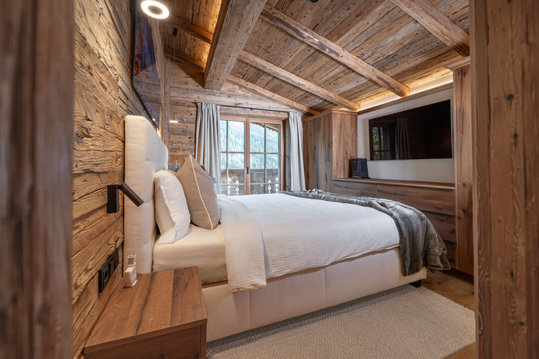 Alpine-style chalet bedroom with reclaimed oak wood and built-in wardrobes.