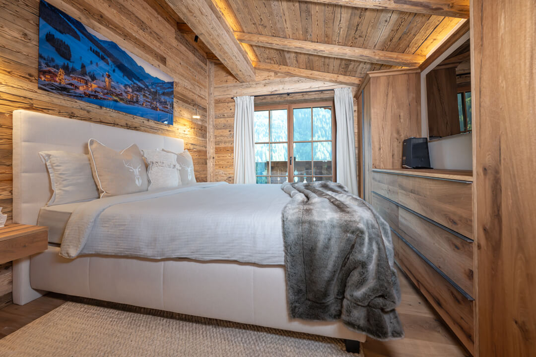 Alpine-style chalet bedroom with reclaimed oak wood and built-in wardrobes.