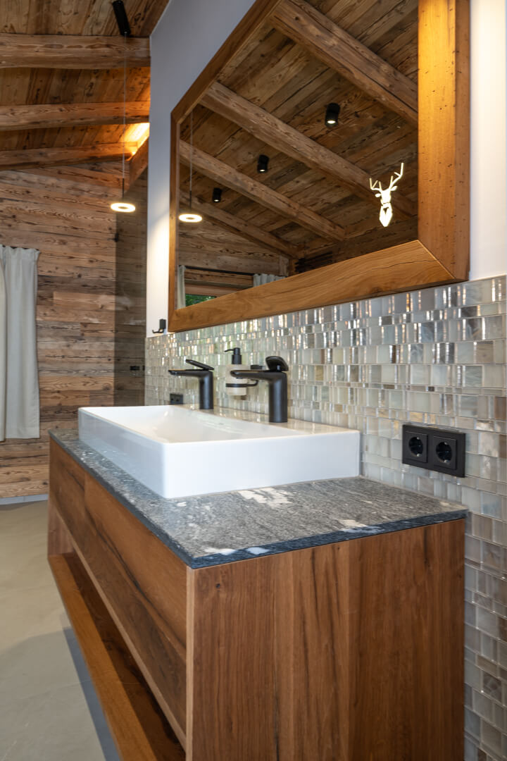 Bathroom with mother-of-pearl wall, oak furniture, and wooden mirror.