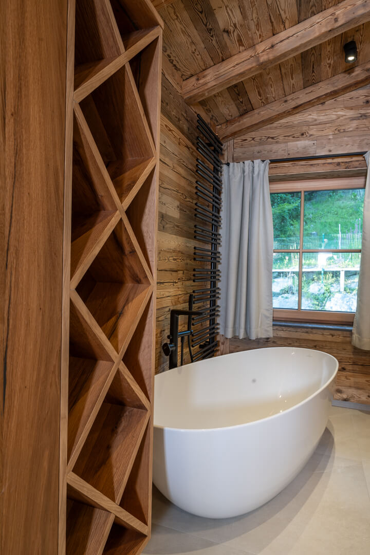 Freestanding bathtub with oak bathroom cabinet and built-in towel storage.