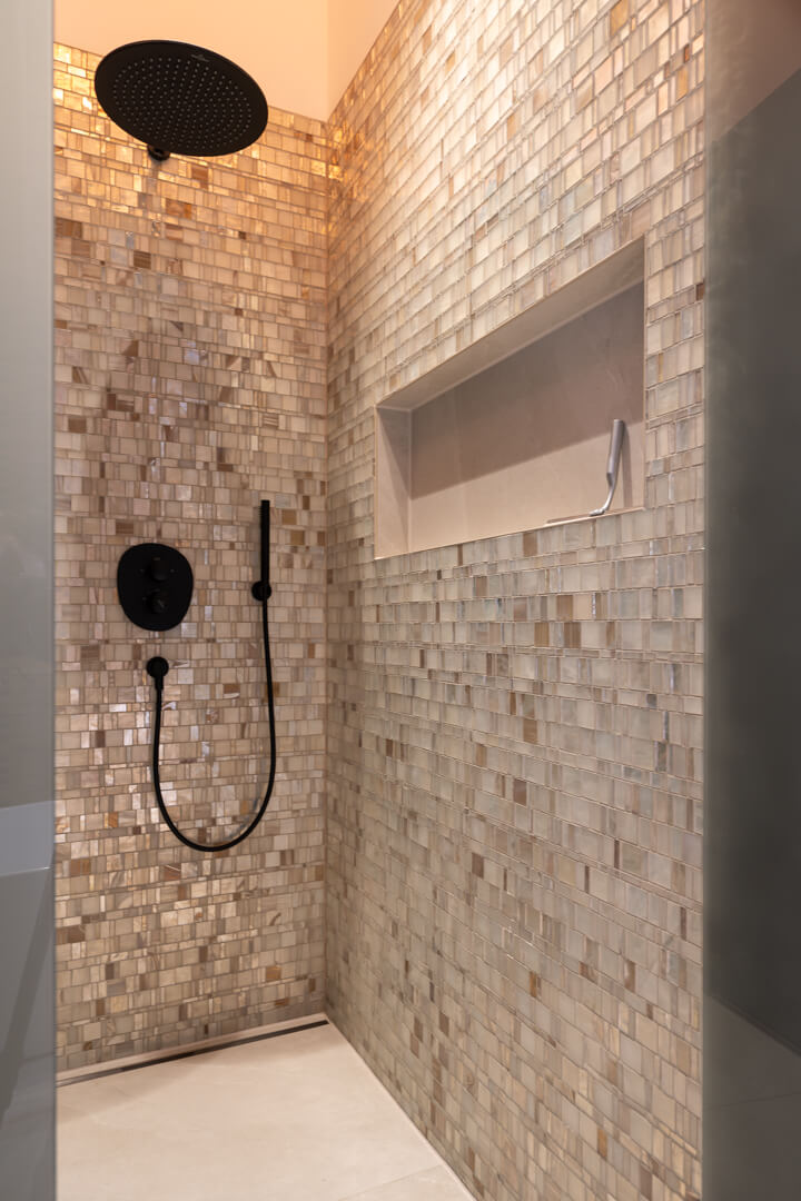 Walk-in rain shower with mother-of-pearl tiles in a luxury chalet bathroom.