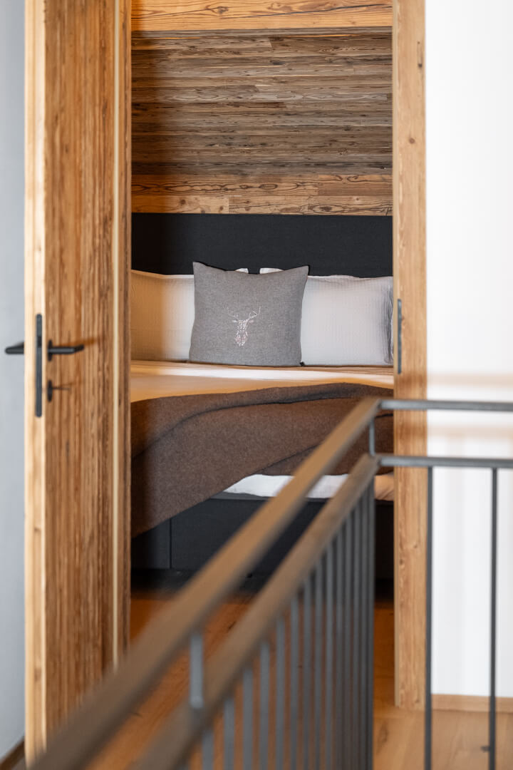 Chalet bedroom entrance with steel railing and reclaimed wood door.