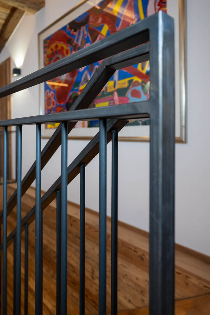 Chalet interior with steel railing, reclaimed wood paneling, and complementary colored artworks.