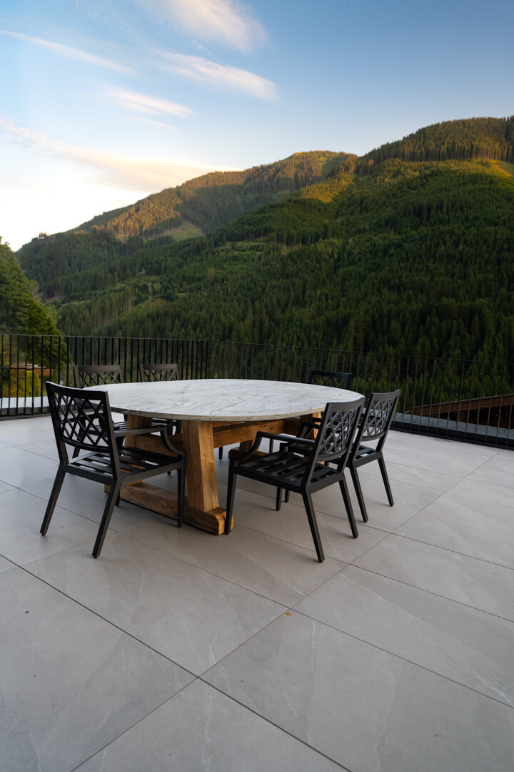 Outdoor dining table with massive stone top and oak base overlooking the Alps.