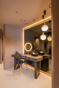 Luxury makeup tables with stone tops and ambient indirect lighting around mirrors in a stylish interior.