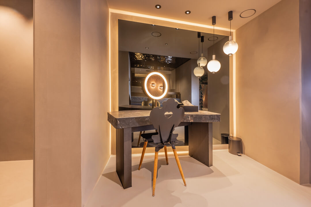 Luxury makeup tables with stone tops and ambient indirect lighting around mirrors in a stylish interior.