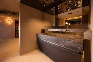 Luxury bathroom with solid stone sink, copper fixtures, and mirrored ceiling.