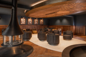 Fireplace room with dark interior, wood paneling, and herringbone floor at Hotel Rössle. Light wooden carpet and displayed black and white portraits.