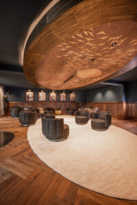 Dark interior, wood paneling, and herringbone floor at Hotel Rössle. Light woolen carpet and displayed black and white portraits.