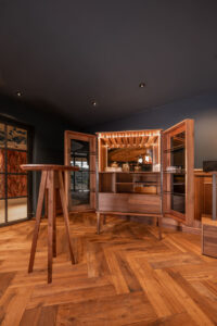 Handcrafted open walnut whiskey cabinet with tinted glass.