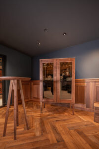 Handcrafted walnut whiskey cabinet with tinted glass.