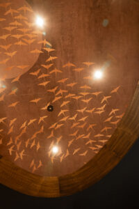 Illuminated wooden ceiling centerpiece with elegant bird pattern.