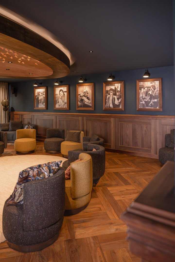 Dark interior, wood paneling, and herringbone flooring at Hotel Rössle. Light woolen carpet and displayed black and white portraits. Cozy chairs.