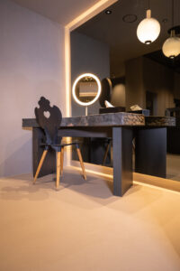 Luxury makeup tables with stone tops and ambient indirect lighting around mirrors in a stylish interior.