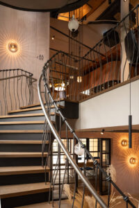 Oak staircase with sculptural steel railing. Decorative wall lighting fixture.