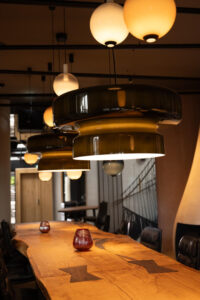 Visible wooden joints connecting a long table with design lamps above