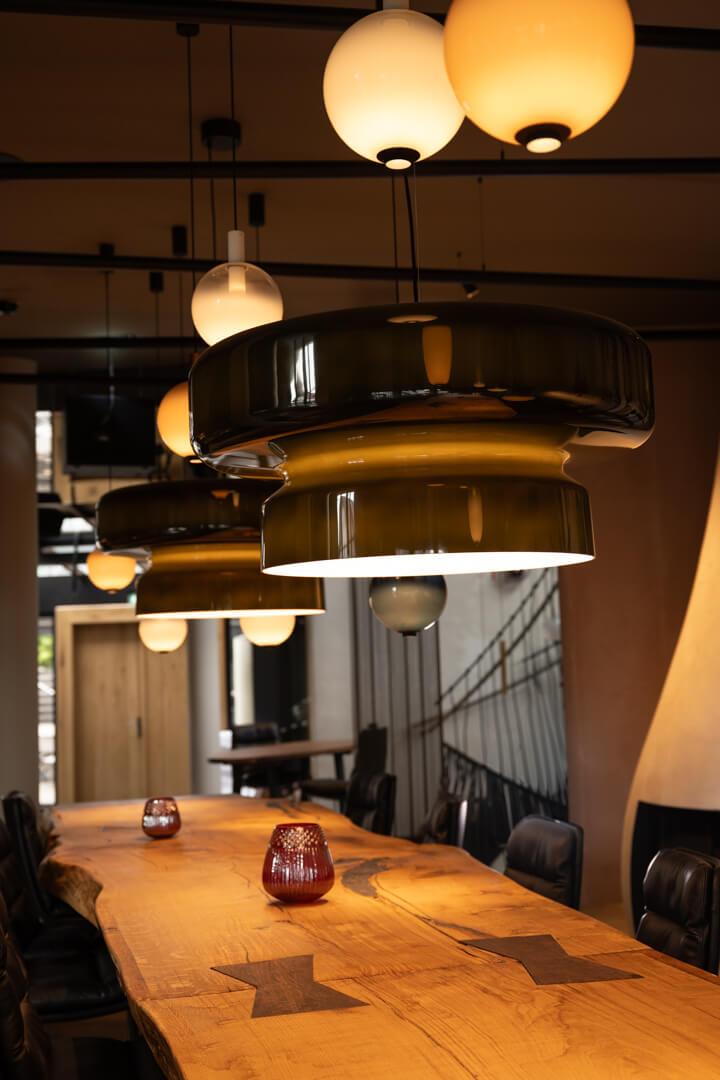 Visible wooden joints connecting a long table with design lamps above