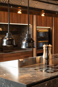 Kitchen with grey stone countertop and walnut wood fronts. Black hangin lamps.