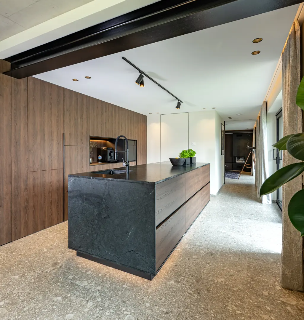 Smoked dark wood kitchen with an island and black natural stone countertops.