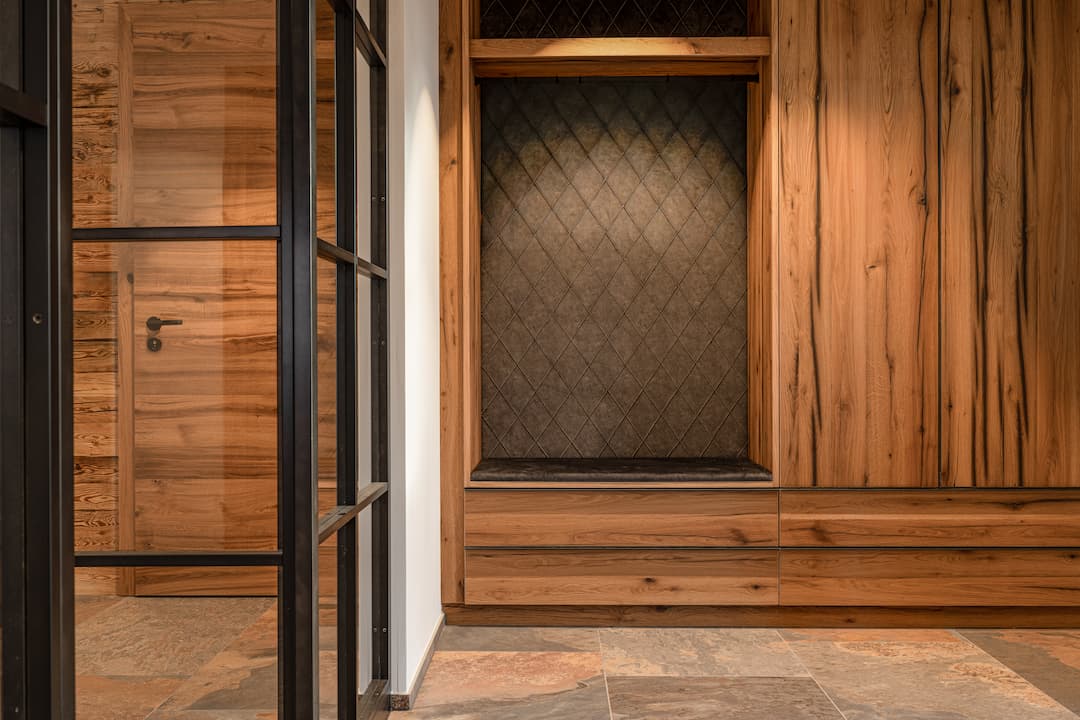 Entryway with a built-in oak wardrobe and upholstered suede bench with a diamond pattern.