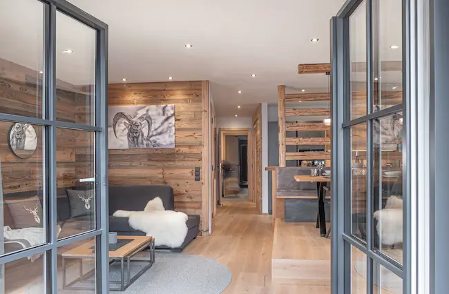 Chalet apartment interior in Alpine style with reclaimed wood and steel-framed terrace doors.