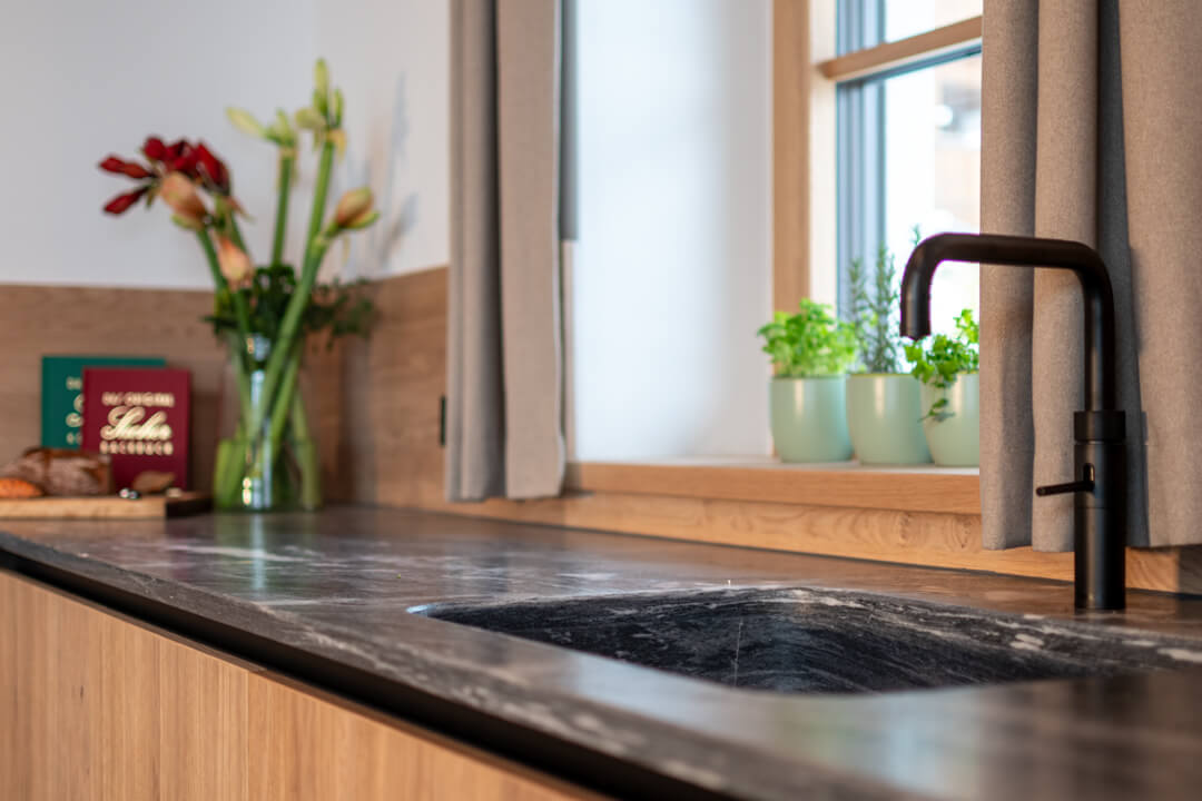 Grey stone countertop, black watertap and oak cabinets kitchen
